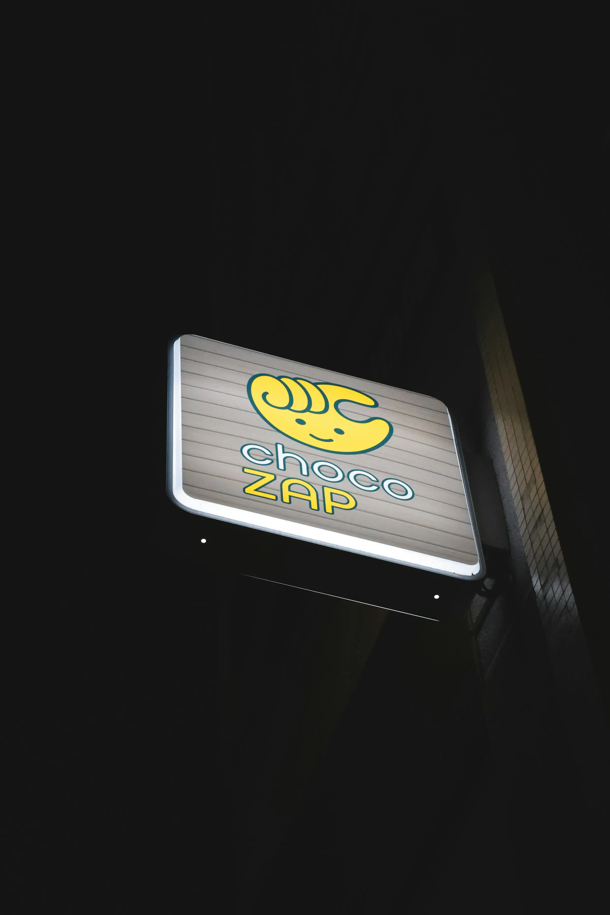 An illuminated shopfront sign after dark.